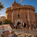 Visiter le Castillet Perpignan, façade rouge et pierre, foule sur la place de Verdun